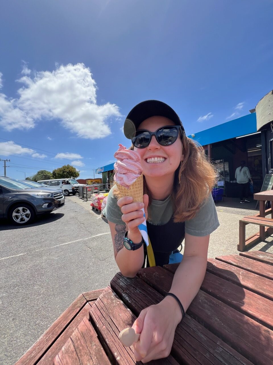 Woman in a hat and sunglasses smiling with a giant real fruit ice cream