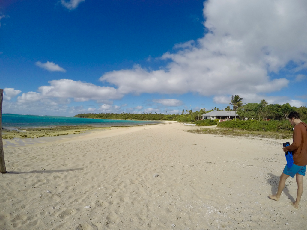 Beach resort in Tonga, beautiful white sand beaches and sparkly blue ocean to the left, palm trees on right