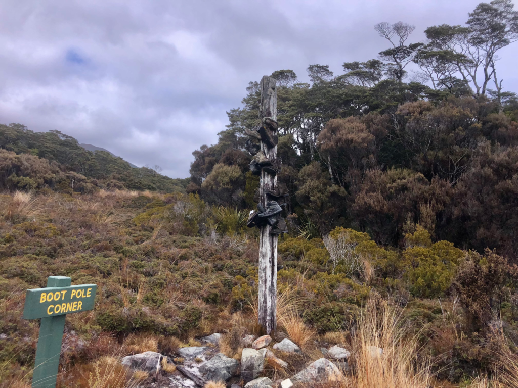 sign that says "boot pole corner" on the heaphy track. there is a big pole with boots tied to it