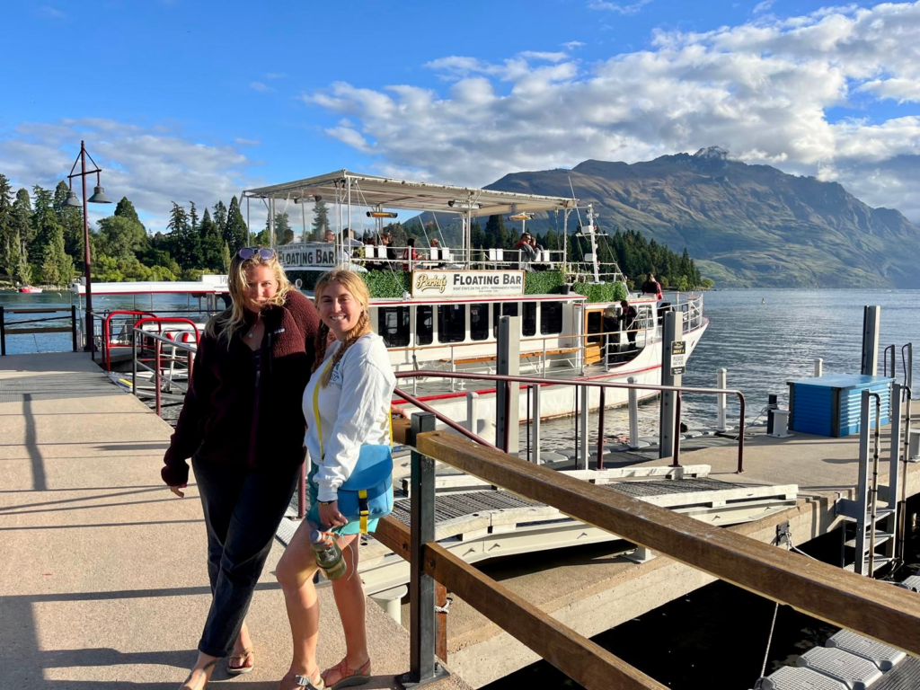 2 women standing on the dock in queenstown in front of perkys floating bar