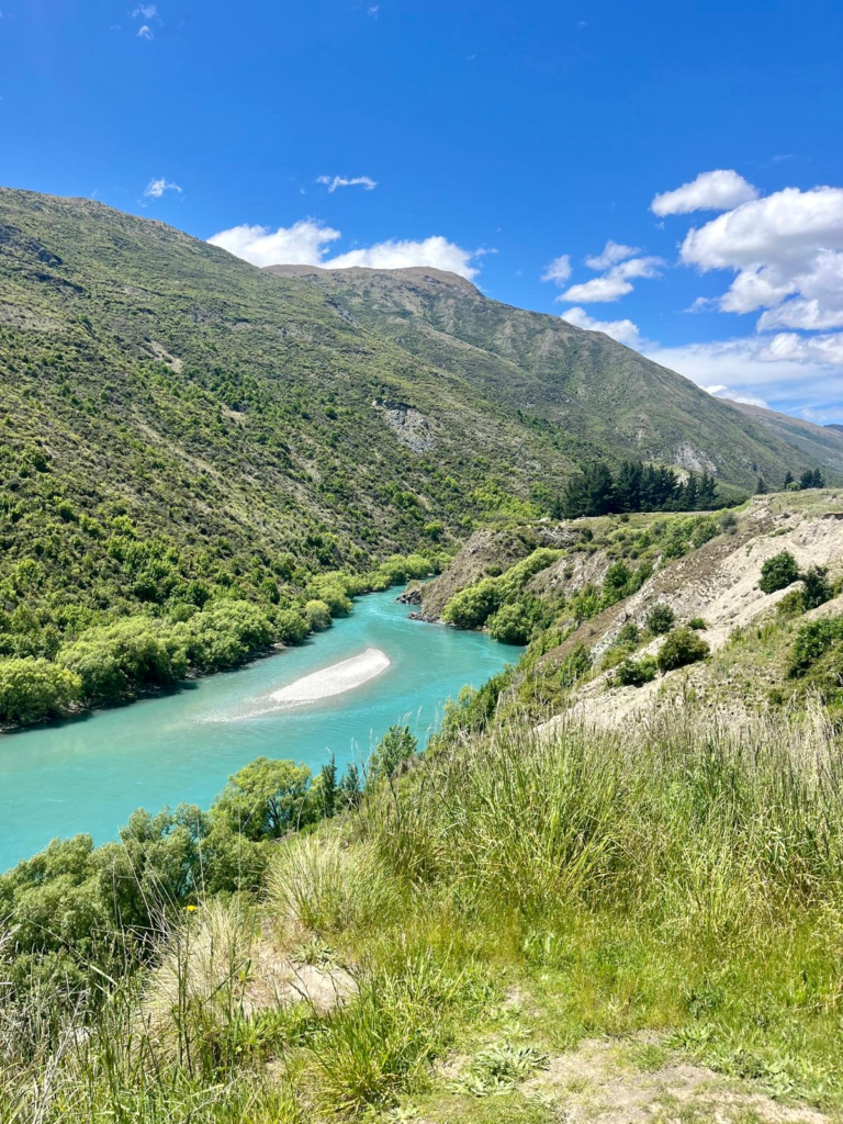 1 week south island itinerary, bright blue river in a gorge between green hills