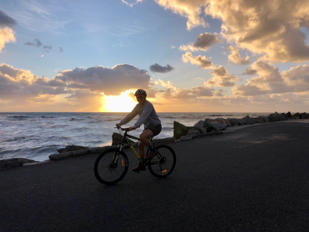 1-day greymouth itinerary. man biking on road at sunset, ocean in background