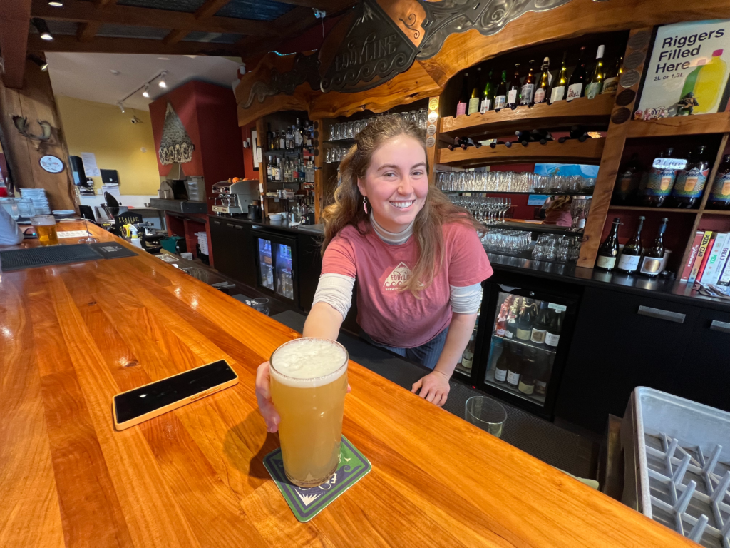 happy woman serving a beer at eddyline pizzaria