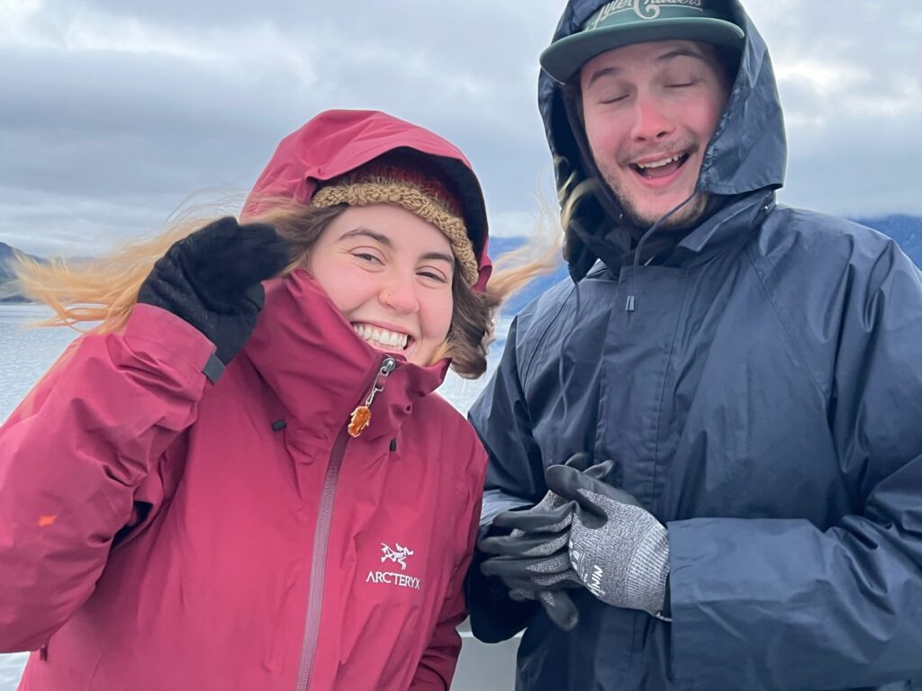 two people smiling in rain gear on a boat in new zealand