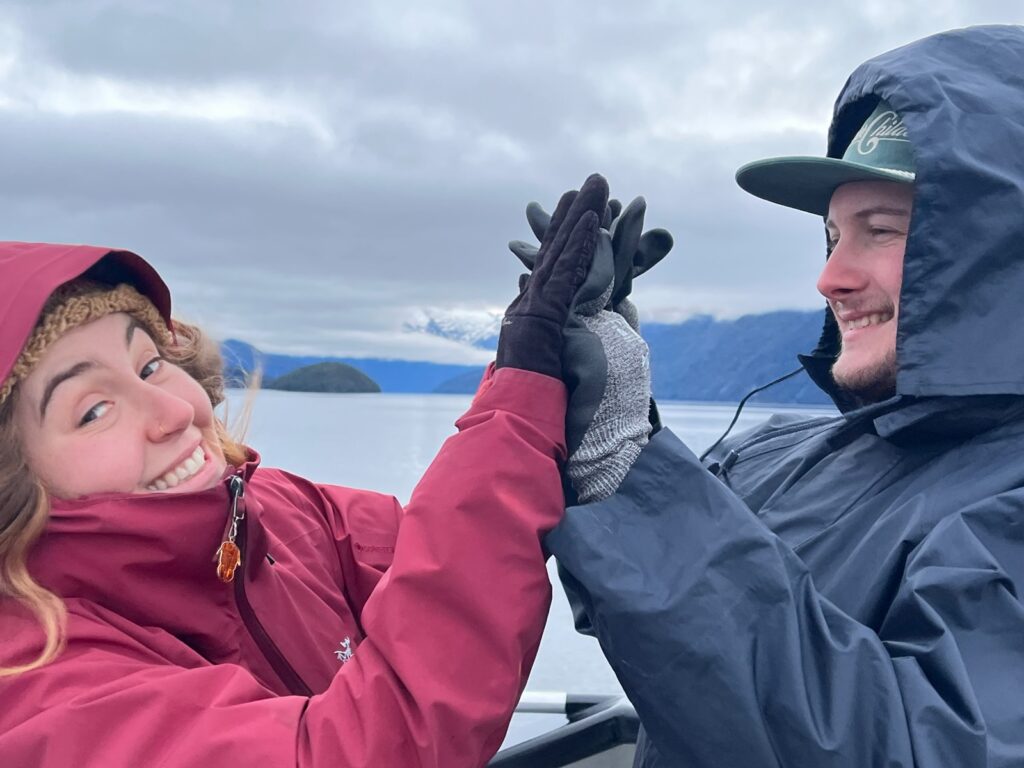 two people high fiveing in te anau on the glow worm tour
