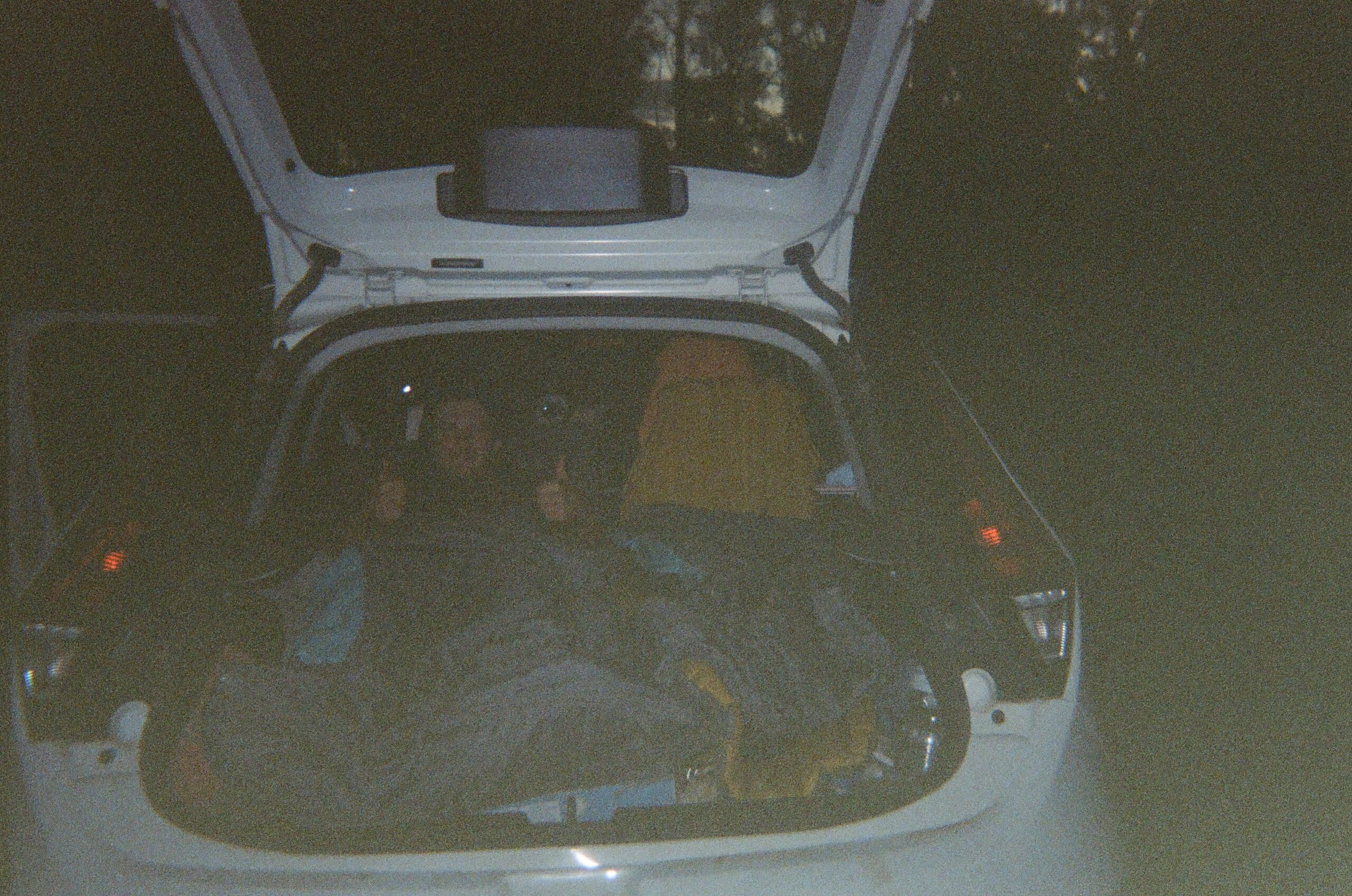 freedom camping in tasmania, trunk of car open with man sleeping inside
