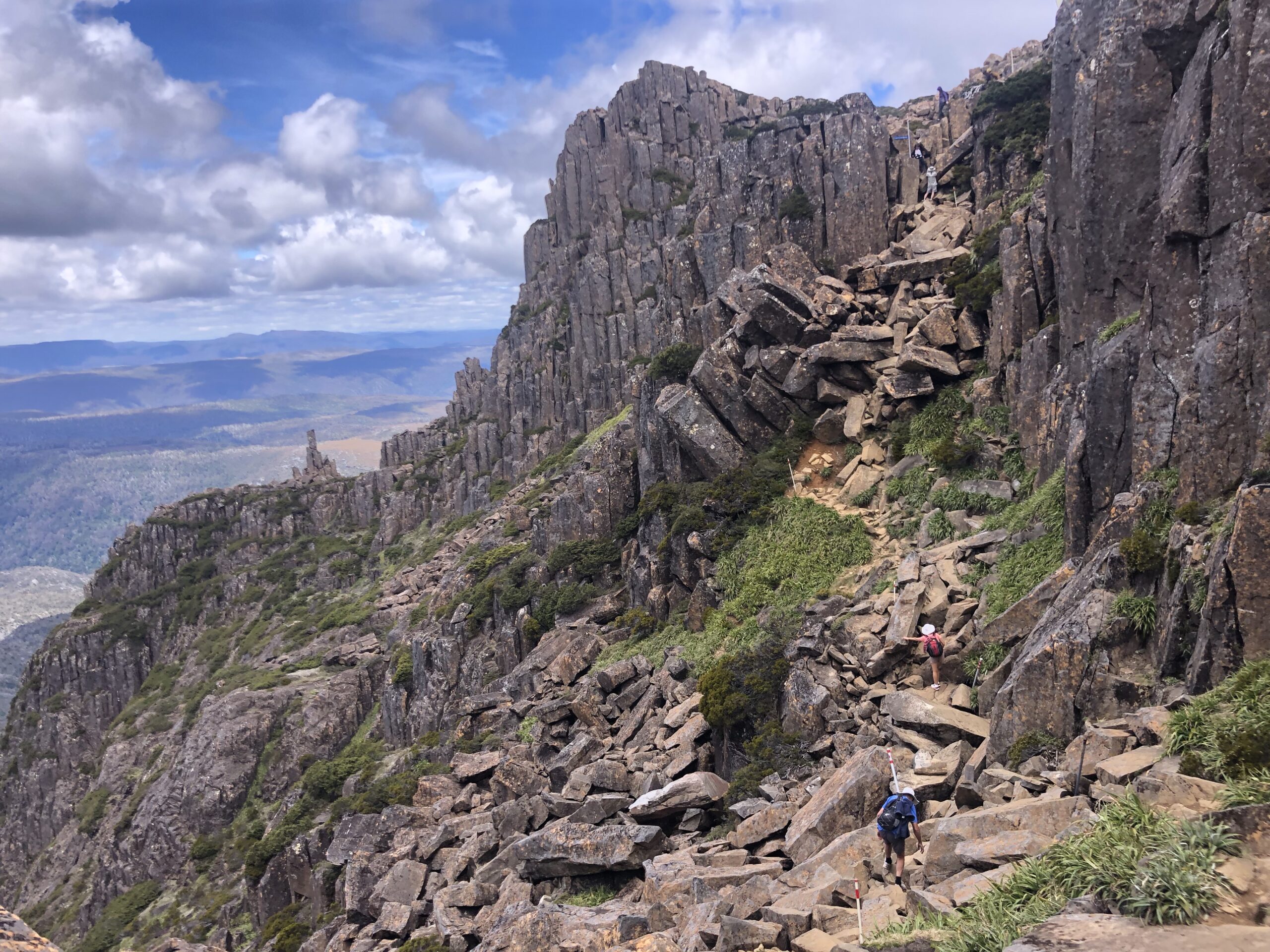 how to freedom camp in tasmania. view of the cliffside of cradle mountain national park with big scraggly rocks emerging from the earth
