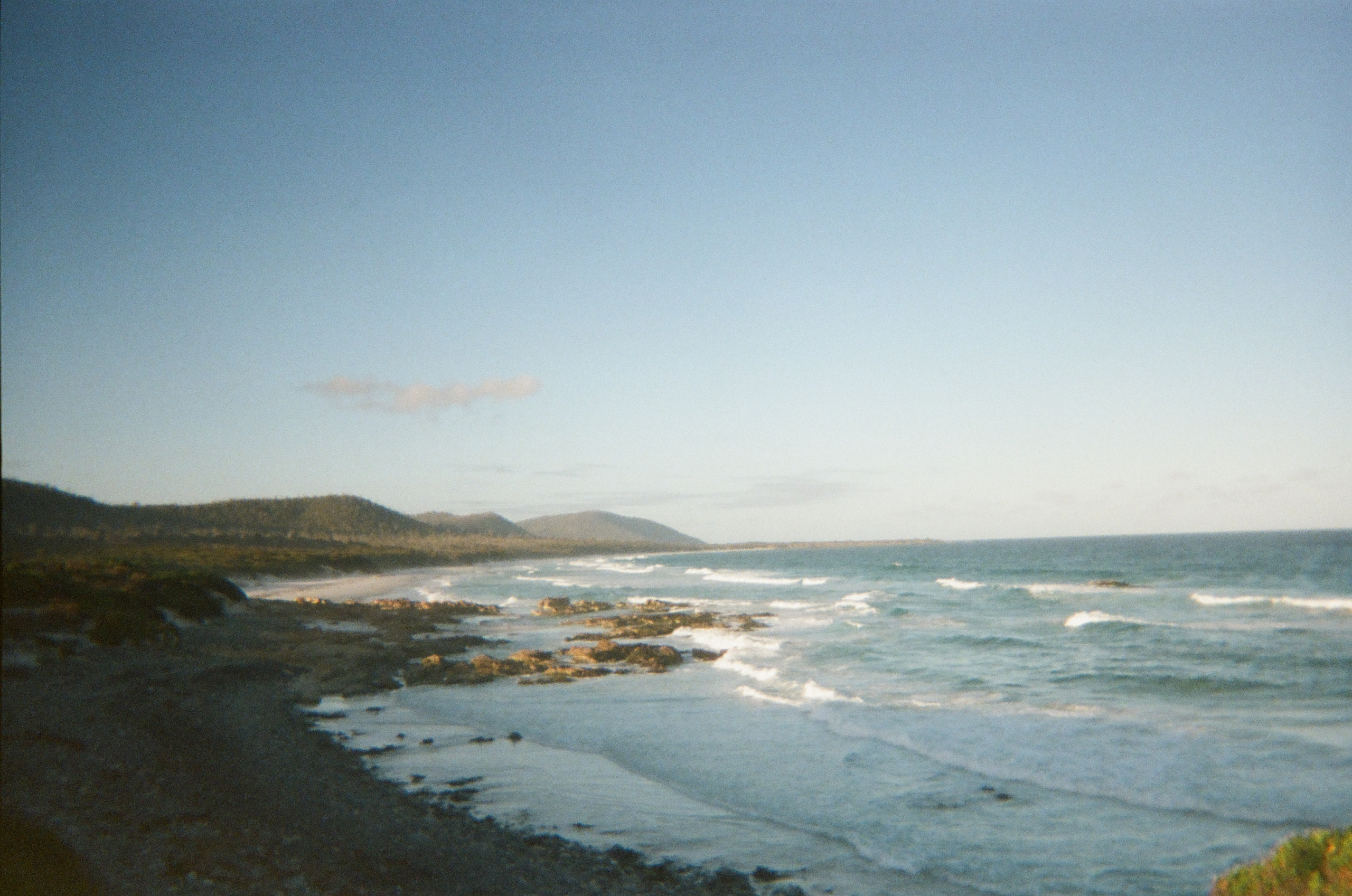 how to freedom camp in tasmania - go to the friendly beaches! Beautiful view of beach with long rolling waves and cliffs