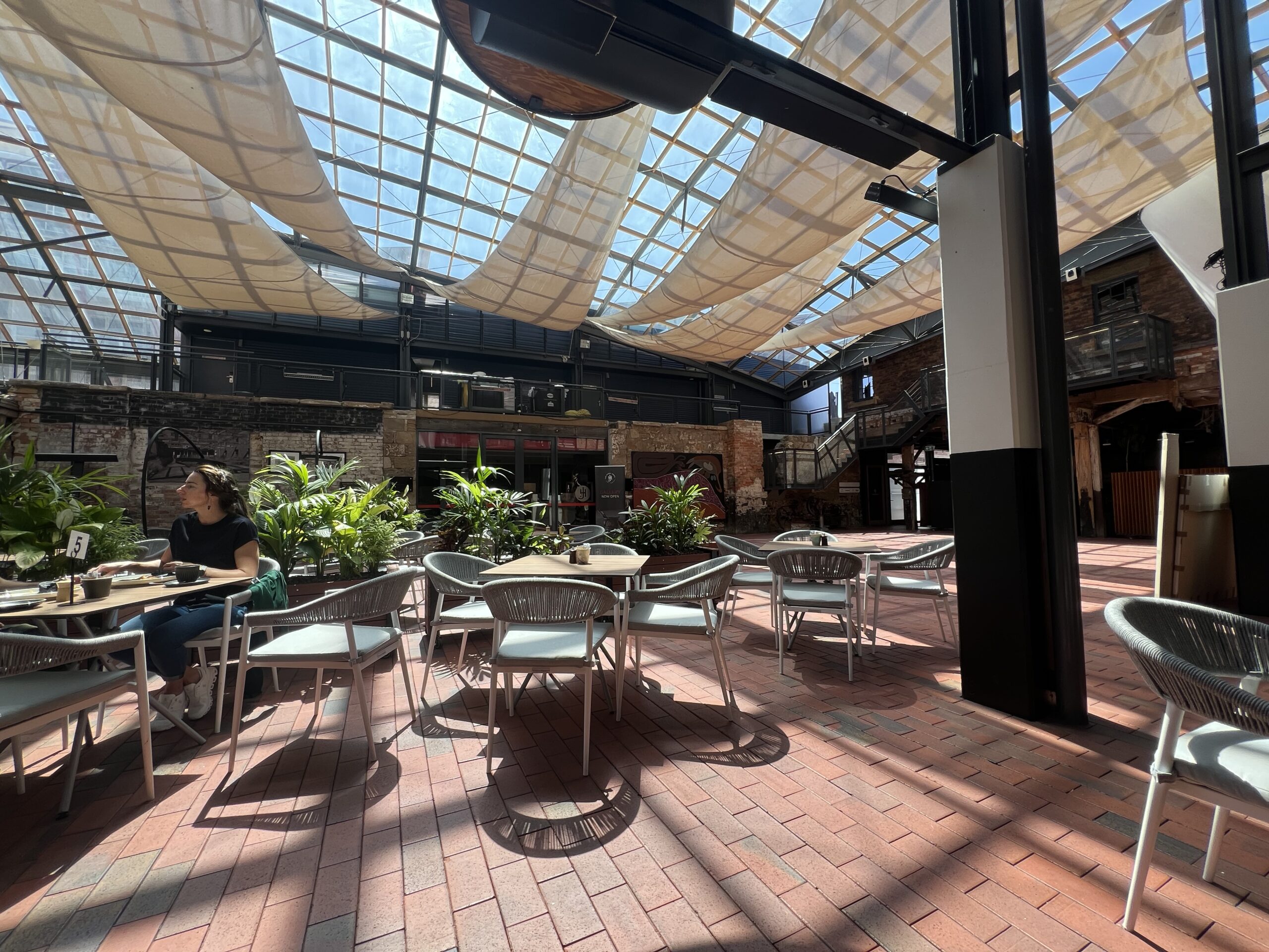 atrium style cafe with red brick, lots of plants and skylights. jam packed cafe in hobart