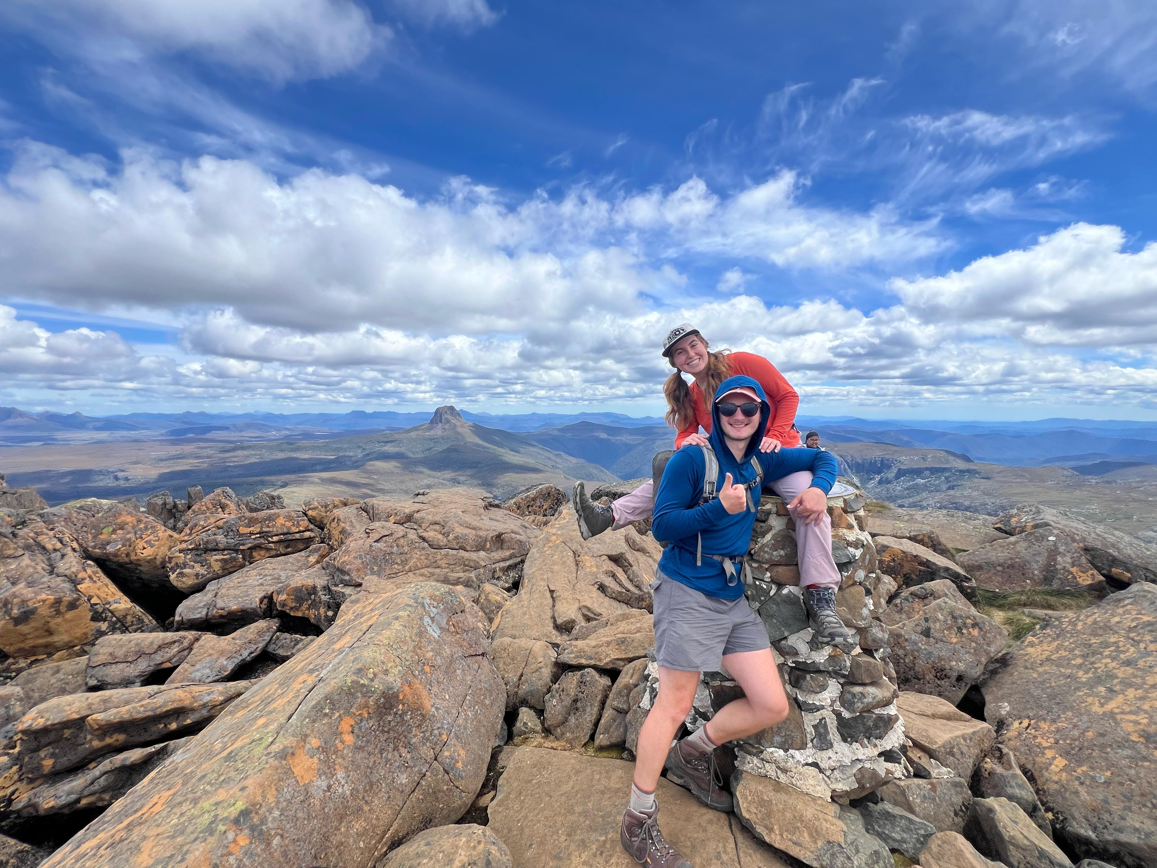 man and woman at the summit of cradle mountain in tasmania. they are standing on large rocks