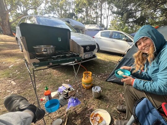 woman sitting in camp chair at free campground in tasmania